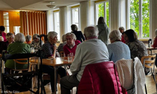 Menschen sitzen an Tischen im Speisesaal des EBZ Bad Alexandersbad und sind angeregt ins Gespräch vertieft.