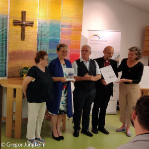 Barbara Schick, Vorstandsmitglied der Versicherungskammer Stiftung, überreicht den Preis an Dekan Jürgen Hacker, Ehrenamtssprecher Udo Müller, Leiterin Elisabeth Peterhoff und Ehrenamtssprecherin Inge Berghammer